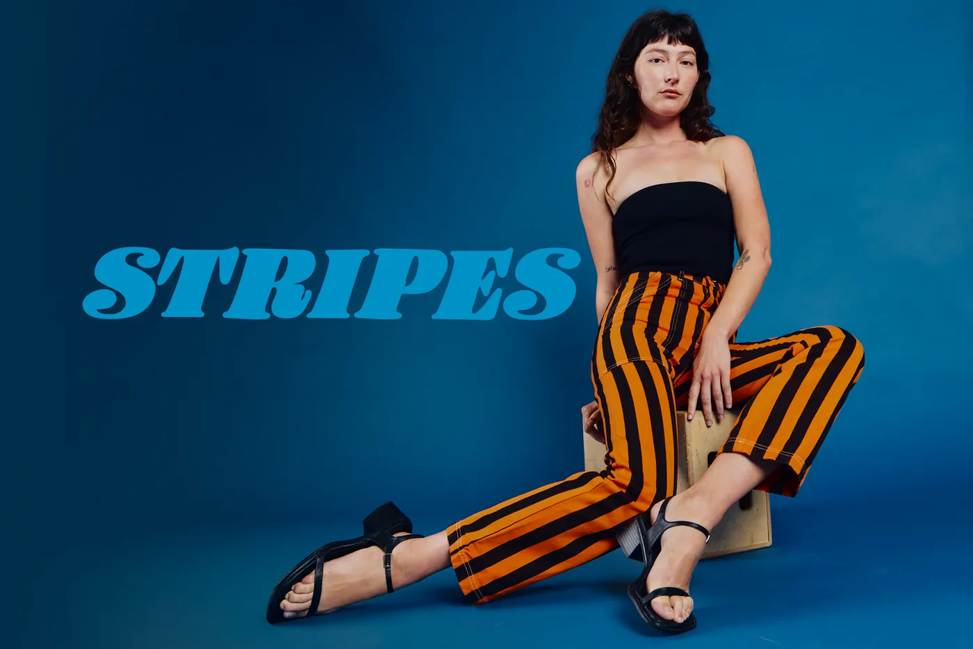 Model wearing orange-and-black striped Big Bud Press pants