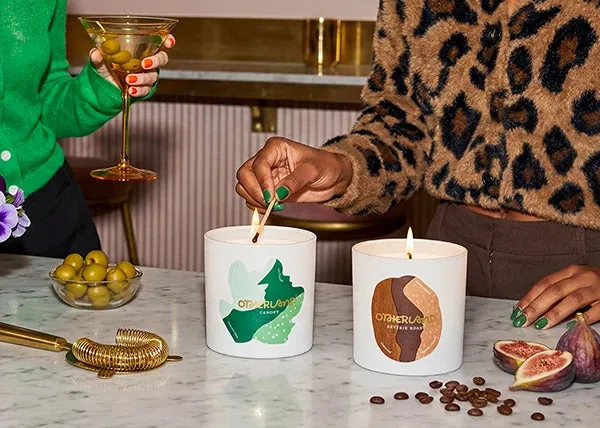 Two decorative Otherland candles being lit on a cocktail table